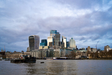 Naklejka premium London’s modern skyline viewed from the Thames River, featuring iconic skyscrapers like the Walkie-Talkie and the Gherkin under a cloudy sky. London district Stock photo