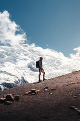 Fototapeta premium Hiker contemplating majestic snowy mountain peak under blue sky