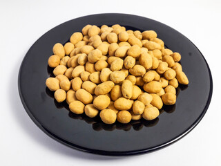 Kacang telur served on a black plate, peanuts coated in egg batter, flour and sweet and savory spices, isolated on a white background