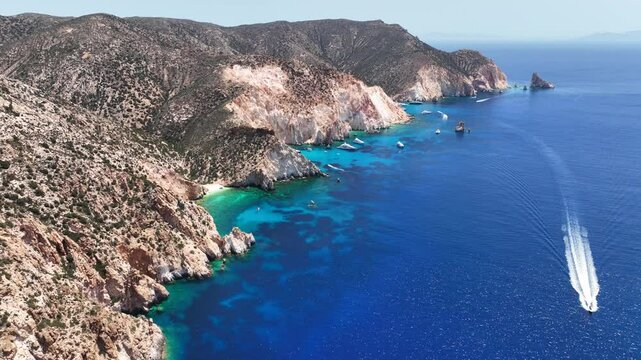 Aerial drone cinematic video of paradise blue bay of uninhabited island of Polyaigos with turquoise crystal clear sea visited by luxury yachts and sail boats resembling a blue lagoon, Cyclades, Greece