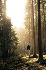 A man in a forest with sunlight shining through the trees