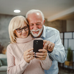 senior couple husband and wife have fun while use mobile phone at home