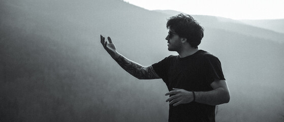 A man in a black shirt stands before a mountain in a photo