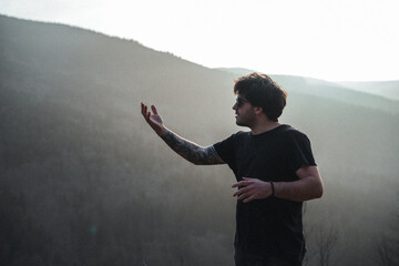 A man in a black shirt stands before a mountain in a photo