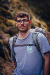 A man with glasses, a purple shirt, and a backpack, outdoor