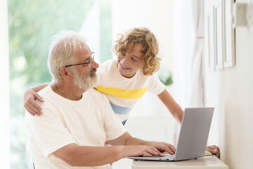 Senior man working on computer with grandchild