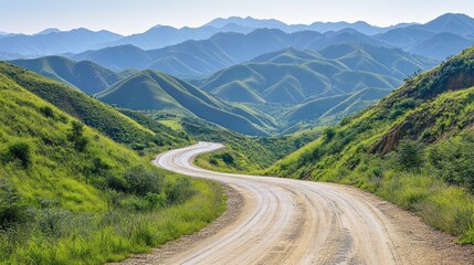 Naklejka premium Winding dirt road through lush green mountains.