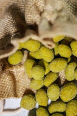 Close-up of vibrant yellow-green wasabi-coated nuts spilling out of a rustic burlap sack. Coated in a fine powder, they appear crunchy and flavorful.