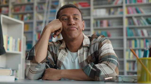 African American man student learner university library thoughtful thinking pensive sad upset exams session displeased male bored guy unhappy annoyed education study high school academy dissatisfied
