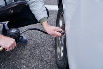 Obraz premium Man checking car tire Pressure with Gauge