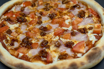 details of the pizza application; juicy pizza from the oven with mushrooms, tomatoes and bacon and sprinkled with parmesan cheese