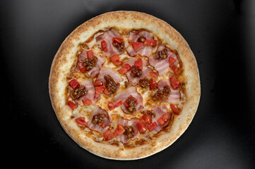 details of the pizza application; juicy pizza from the oven with mushrooms, tomatoes and bacon and sprinkled with parmesan cheese