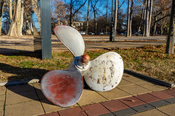 Alte Schiffspropeller-Ausstellung in Si&oacute;fok, Ungarn, vor herbstlicher Kulisse und blauem Himmel
