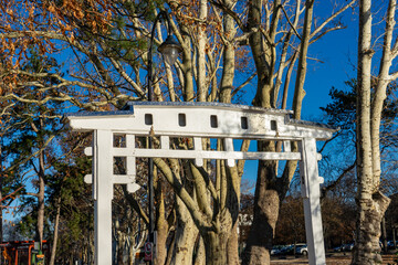 Traditionelles wei&szlig;es Holztor in Si&oacute;fok, Ungarn, mit herbstlicher Kulisse und blauem Himmel