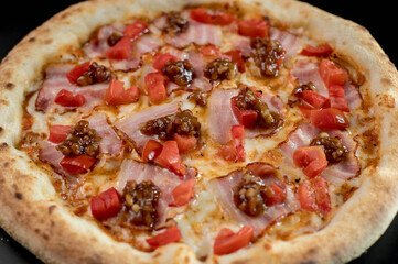 details of the pizza application; juicy pizza from the oven with mushrooms, tomatoes and bacon and sprinkled with parmesan cheese
