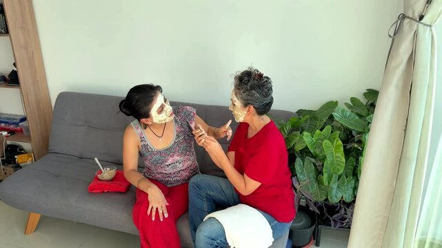 Women applying skull face mask for day of the dead