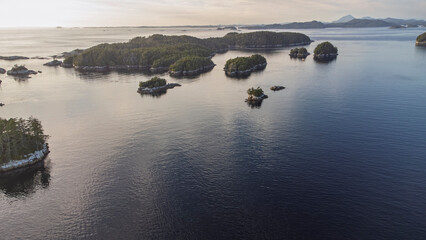 Islands sitting in the calm waters off Calvert Island, British Columbia as the sun set washes them in soft light 