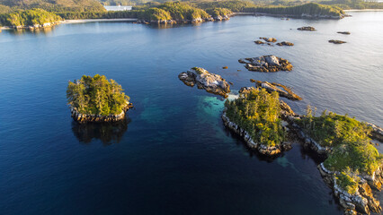 Small islands dot the calm sea next to Calvert Island, British Columbia, Canada. Islands bathed in...