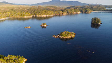 Calvert Island washes in dark sunlight as the sun being to set. A small mountain in the background 