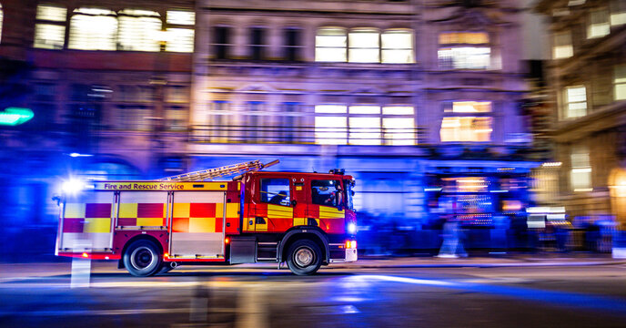 fast red firetruck on emergency call in London city center. lights on and firefighters inside. motion effect. panning effect. fire brigade UK