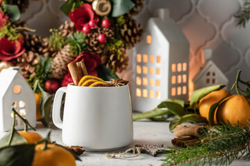 Mulled wine with cinnamon, spices, tangerine and orange on light festive background, traditional drink for winter holiday