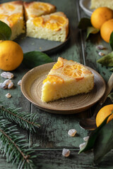 Upside down orange tangerine cake or pie slice on a plate on green wooden background. Fruit citrus pastry. Homemade winter baking