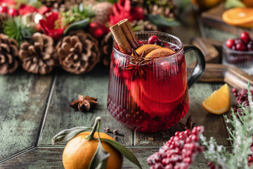 Mulled red wine with cinnamon, spices, tangerine, orange and cranberry on wooden festive...