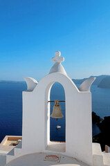 Old bell on a dome Christian church against the background of the blue Caldera of Santorini island taken closeup.