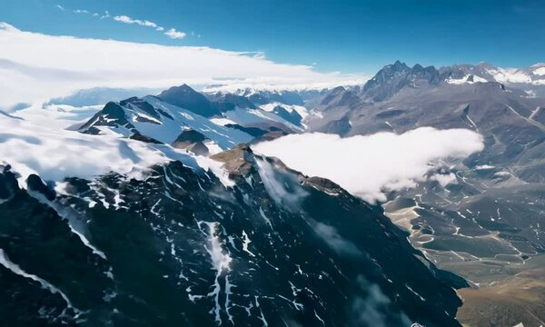 Aerial View of Majestic Snow-Capped Mountains Piercing Through Clouds