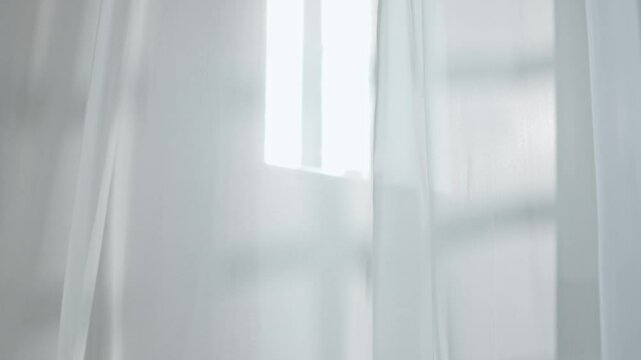 Transparent white silk soft fabrics floating with light shining through, shadows and shades reflected on the textile, close view.