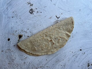 Empanada made with corn masa cooking on a comal in Oaxaca, Mexico