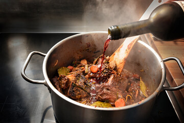 Red wine is poured into a stainless steel pot to deglaze the roasted ingredients such as bones, meat and vegetables, cooking steps for a rich stock or demi glace, copy space