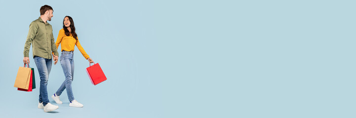 Man and woman contently strolling with bright shopping bags, sharing a cheerful conversation on a...