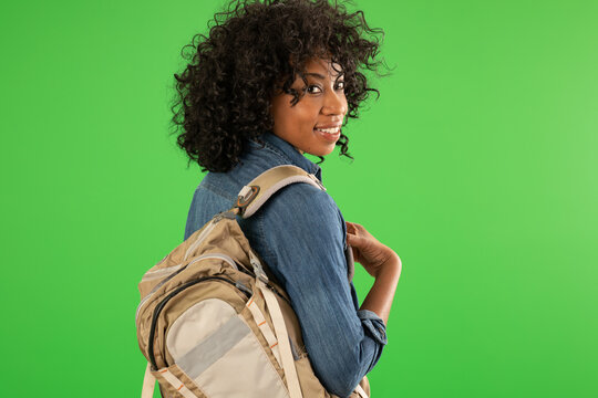 Portrait of pretty African American female with backpack smiling on greenscreen