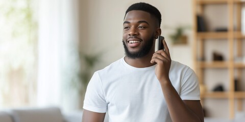 Obraz premium A man is talking on his cell phone in a living room. He is smiling and he is enjoying the conversation