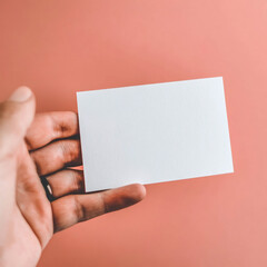 Obraz premium Male hand holding a white card against a soft pink background. The composition highlights warmth, minimalism, and a delicate design, ideal for branding or communication purposes. Generated with AI