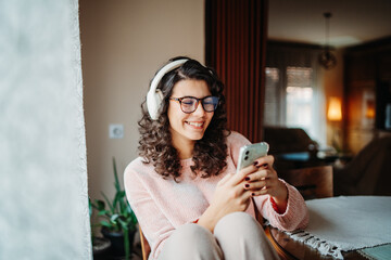 Young caucasian woman enjoying music on wireless headphones at home	