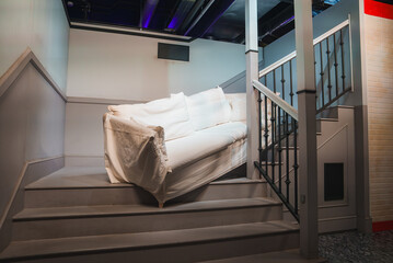 A white couch is positioned on a staircase with a wooden railing, part of a Friends themed...
