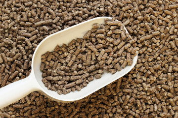 Wood cat litter and plastic scoop. Hygienic filler for pets. Pressed wood, large granules. Pellets. A pile of wood pellets. Filler for dogs, cats, domestic rodents