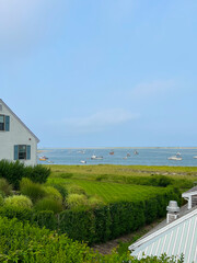 A view of the harbor from a building, with fishing boats on the water and lush greenery surrounding the scene, under a clear sky with a hint of clouds.