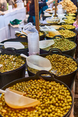 Assortment of green olives in brine displayed in large containers at a market