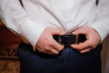 Groom Adjusting Belt Before Wedding Ceremony
