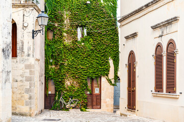 A picturesque square with a ivy-covered wall and a bicycle in the historical center of Otranto province of Lecce, Salento area, Puglia region, Italy