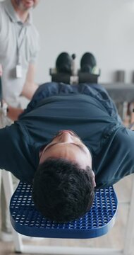 People, inversion table and fitness as physiotherapist for exercise, wellness or muscle relief. Men, stretching and patient for back pain, support and recovery in physiotherapy, injury and healthcare
