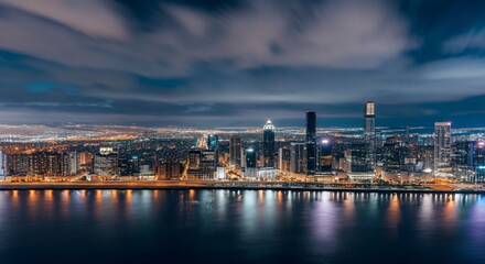 Fototapeta premium A panoramic view of a city skyline at dusk with glowing lights reflecting on the water
