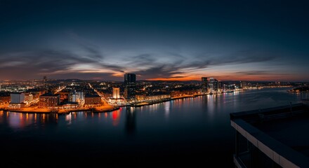Obraz premium A panoramic view of a city skyline at dusk with glowing lights reflecting on the water