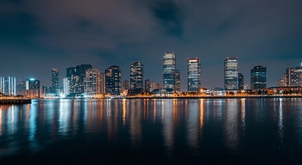 Fototapeta premium A panoramic view of a city skyline at dusk with glowing lights reflecting on the water