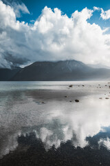 cloudy mountains being reflected off a lake.