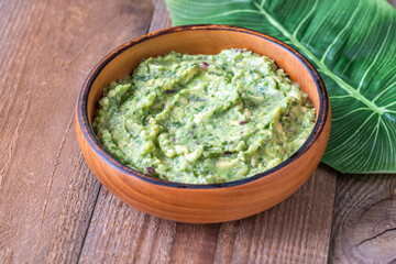 Rustic Guacamole in Wooden Bowl with Fresh Green Leaf