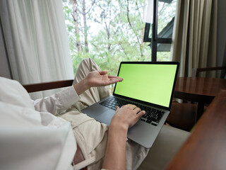 Fototapeta premium Young adult working on laptop in minimalistic indoor space with natural light, showcasing modern lifestyle and remote work concept